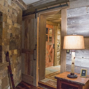 Esempio di una camera matrimoniale stile rurale con pavimento in legno massello medio, camino ad angolo e cornice del camino in pietra