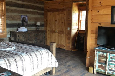 Diseño de dormitorio rural grande con paredes marrones, suelo de madera en tonos medios y suelo marrón