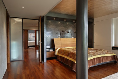 Modelo de dormitorio actual de tamaño medio sin chimenea con paredes blancas y suelo de madera en tonos medios