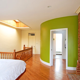Diseño de dormitorio tipo loft, bohemio, grande, con paredes verdes, suelo de madera en tonos medios, marco de chimenea de ladrillo, chimenea tradicional y suelo marrón