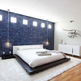 Modelo de dormitorio principal, contemporáneo, grande, con paredes beige, suelo de madera en tonos medios, chimenea tradicional y marco de chimenea de yeso