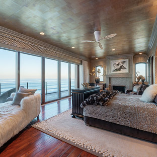 Imagen de dormitorio principal, exótico, extra grande, con paredes multicolor, suelo de madera en tonos medios, chimenea tradicional, marco de chimenea de baldosas y/o azulejos y suelo marrón