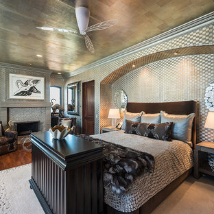 Diseño de dormitorio principal, exótico, extra grande, con suelo de madera oscura, chimenea tradicional, marco de chimenea de baldosas y/o azulejos, paredes multicolor y suelo marrón
