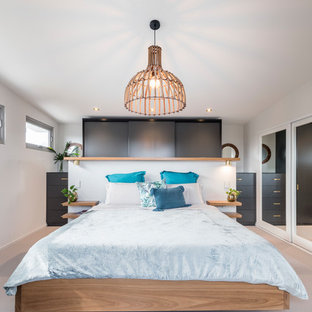 This is an example of a tropical bedroom in Newcastle - Maitland with white walls, light hardwood floors and beige floor.
