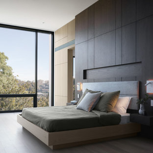 Design ideas for an expansive modern master bedroom in Sydney with light hardwood floors, beige floor and brown walls.