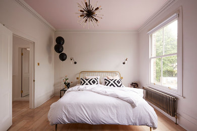 Inspiration for a medium sized scandinavian grey and brown bedroom in London with pink walls, medium hardwood flooring and brown floors.