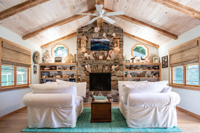 ニューヨークにあるビーチスタイルのおしゃれな主寝室 (白い壁、淡色無垢フローリング、標準型暖炉、石材の暖炉まわり、ベージュの床)