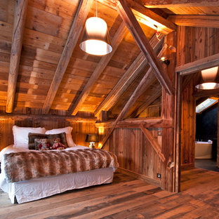 Idée de décoration pour une grand chambre parentale chalet avec un sol en bois foncé et un mur marron.