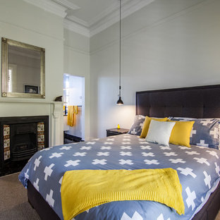This is an example of a transitional bedroom in Hobart with grey walls, carpet, a standard fireplace and brown floor.