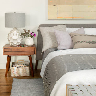 Example of a danish medium tone wood floor and brown floor bedroom design in Denver with white walls