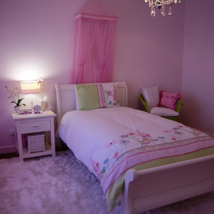 Modelo de dormitorio contemporáneo, de tamaño medio, con paredes rosas y suelo de madera en tonos medios