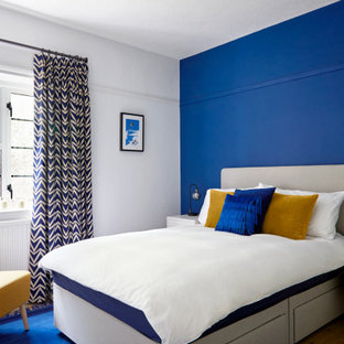Inspiration for a contemporary guest bedroom in Surrey with medium hardwood flooring, no fireplace, brown floors and blue walls.