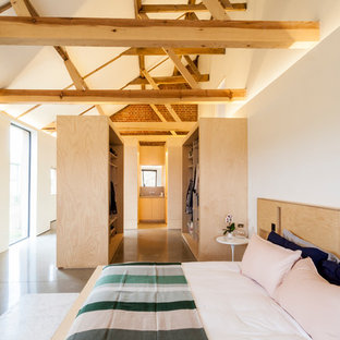 Diseño de dormitorio de estilo de casa de campo, de tamaño medio, sin chimenea, con paredes blancas, suelo de cemento y suelo gris