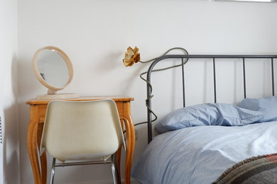Modelo de habitación de invitados contemporánea pequeña con paredes blancas, suelo laminado y suelo marrón