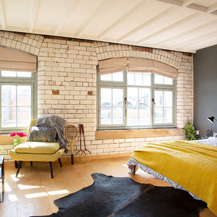 This is an example of a large industrial master bedroom in Other with beige walls, light hardwood flooring and beige floors.