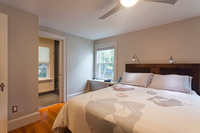 Modelo de dormitorio actual sin chimenea con paredes grises y suelo de madera en tonos medios