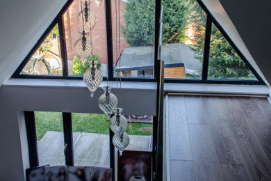 This is an example of a large contemporary mezzanine bedroom in West Midlands with white walls, dark hardwood flooring and brown floors.