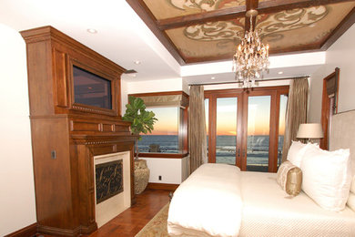 Mediterranes Hauptschlafzimmer mit beiger Wandfarbe, dunklem Holzboden, Kamin und Kaminumrandung aus Stein in Los Angeles