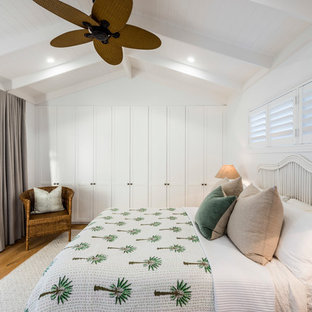 Design ideas for a large beach style master bedroom in Gold Coast - Tweed with white walls, medium hardwood floors and brown floor.
