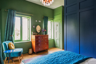 Modelo de habitación de invitados contemporánea con paredes verdes y suelo de madera en tonos medios