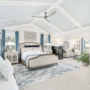 Foto de dormitorio principal, abovedado y madera, costero, extra grande, madera, con paredes beige, moqueta, chimenea de doble cara, marco de chimenea de baldosas y/o azulejos, suelo beige y madera