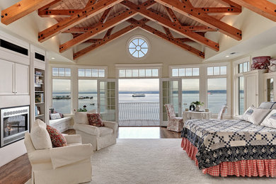 Large beach style master bedroom in Seattle with medium hardwood flooring, a standard fireplace, a metal fireplace surround and beige walls.