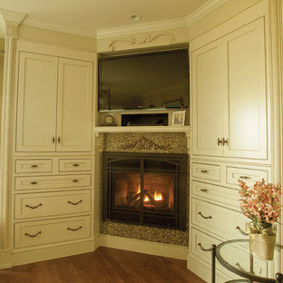 Imagen de habitación de invitados actual, grande, con paredes beige, suelo de madera en tonos medios, chimenea de esquina y marco de chimenea de baldosas y/o azulejos