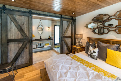 Uriges Hauptschlafzimmer ohne Kamin mit weißer Wandfarbe und braunem Holzboden in Toronto