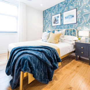 Contemporary bedroom in London with blue walls, light hardwood flooring and beige floors.