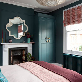 Design ideas for a mid-sized eclectic guest bedroom in London with blue walls, a standard fireplace and a metal fireplace surround.