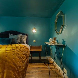 Modelo de dormitorio principal, ecléctico, pequeño, sin chimenea, con paredes azules, suelo laminado y suelo marrón