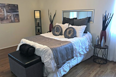 Modelo de dormitorio principal minimalista de tamaño medio sin chimenea con paredes beige, suelo de madera en tonos medios y suelo marrón