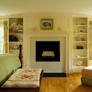 Imagen de dormitorio principal, clásico, grande, con paredes beige, suelo de madera en tonos medios, estufa de leña y marco de chimenea de piedra