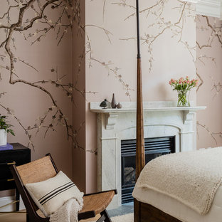 Example of a transitional medium tone wood floor and brown floor bedroom design in Boston with pink walls and a standard fireplace