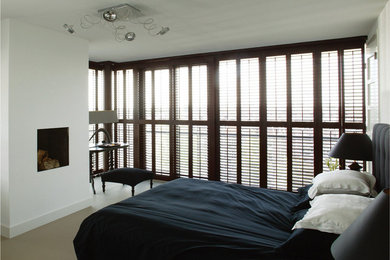 Imagen de dormitorio clásico de tamaño medio con paredes blancas, todas las chimeneas, marco de chimenea de yeso y suelo de cemento
