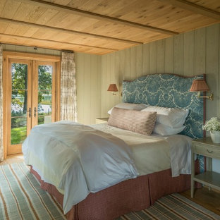 Diseño de dormitorio principal, rural, grande, con paredes grises, suelo de madera clara y suelo marrón