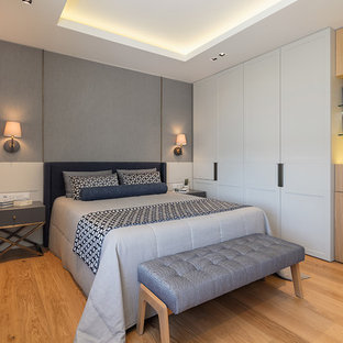 Mid-sized trendy master medium tone wood floor and brown floor bedroom photo in New York with gray walls and no fireplace