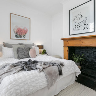This is an example of a contemporary bedroom in Hobart with white walls, medium hardwood floors, a standard fireplace and a wood fireplace surround.