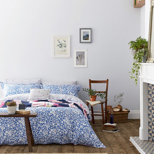 Inspiration for a contemporary guest bedroom in Sussex with blue walls, dark hardwood flooring, a standard fireplace and brown floors.