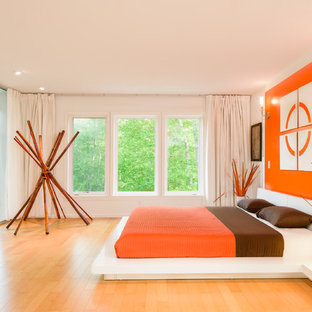 Foto på ett funkis sovrum, med vita väggar, mellanmörkt trägolv och orange golv