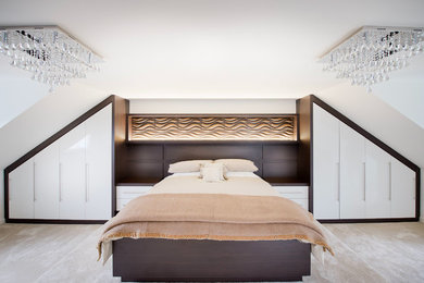 This is an example of a large modern master bedroom in Manchester with white walls and carpet.