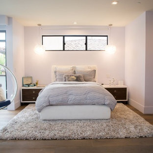 Imagen de dormitorio actual, grande, con paredes púrpuras, suelo de madera en tonos medios y suelo marrón