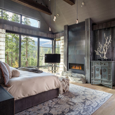 Example of a mountain style master light wood floor and beige floor bedroom design in Denver with a ribbon fireplace