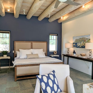 Modelo de dormitorio principal, de estilo americano, de tamaño medio, con paredes blancas, suelo de pizarra, chimenea de esquina, marco de chimenea de yeso y suelo gris
