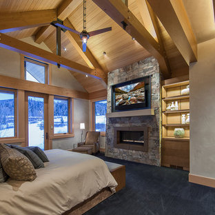 Imagen de dormitorio principal, actual, grande, con paredes beige, moqueta, chimenea tradicional, marco de chimenea de piedra y suelo azul