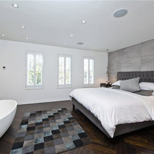 This is an example of a medium sized contemporary master and grey and brown bedroom in London with dark hardwood flooring, brown floors and grey walls.