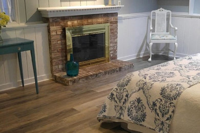 ニューヨークにある中くらいなシャビーシック調のおしゃれな主寝室 (グレーの壁、無垢フローリング、標準型暖炉、レンガの暖炉まわり) のインテリア