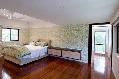 Modelo de dormitorio principal actual grande con paredes verdes, suelo de madera oscura y suelo marrón