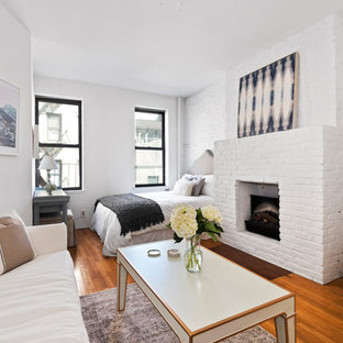 Idées déco pour une chambre parentale contemporaine de taille moyenne avec un mur blanc, un sol en bois foncé, une cheminée standard, un manteau de cheminée en brique et un sol marron.