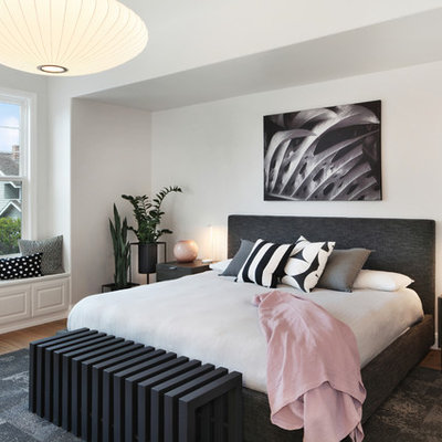 Example of a large trendy master medium tone wood floor and brown floor bedroom design in Orange County with white walls
